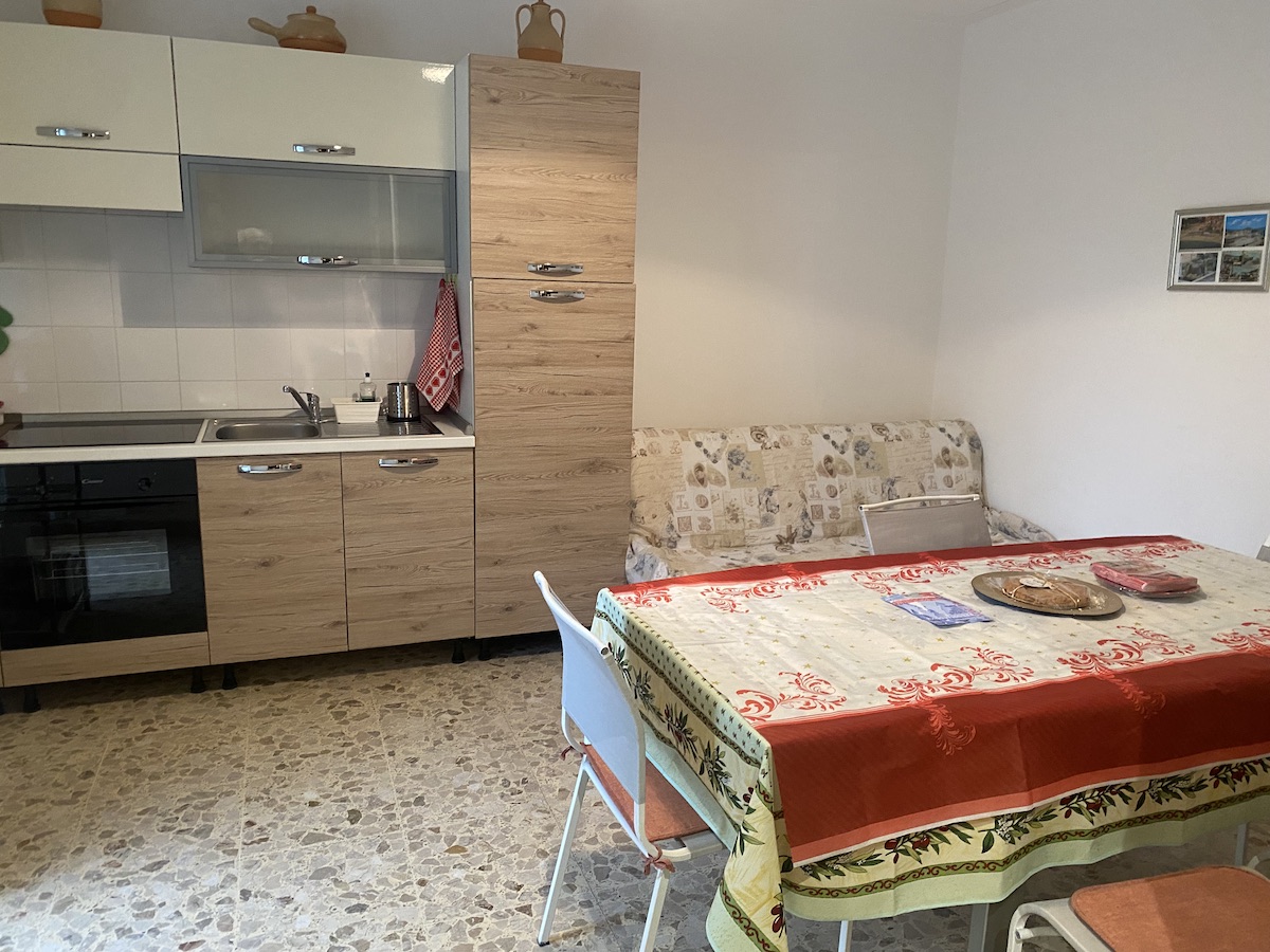 Cucina attrezzata e luminosa in appartamento per vacanze, con zona pranzo, elettrodomestici moderni e ambiente accogliente ideale per soggiorni rilassanti.